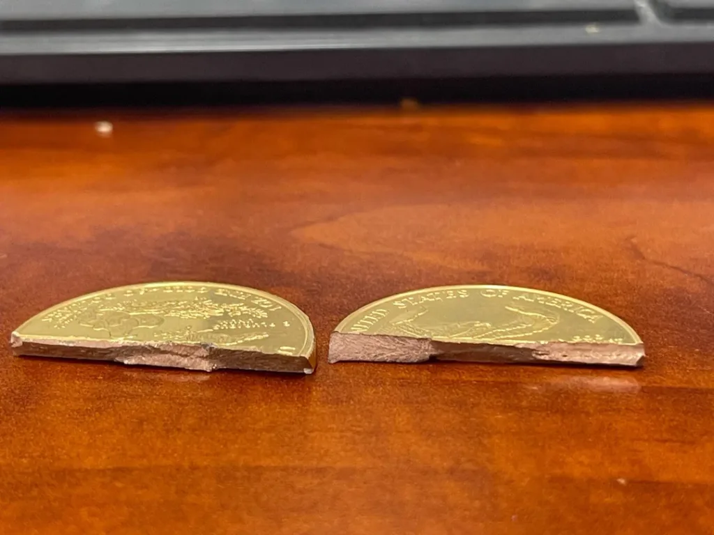 A counterfeit gold coin with a tungsten core and thin gold plating compared to a genuine solid gold coin.